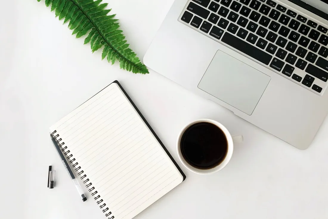 A tidy preparer's workspace — laptop, notebook and coffee on a clean desk